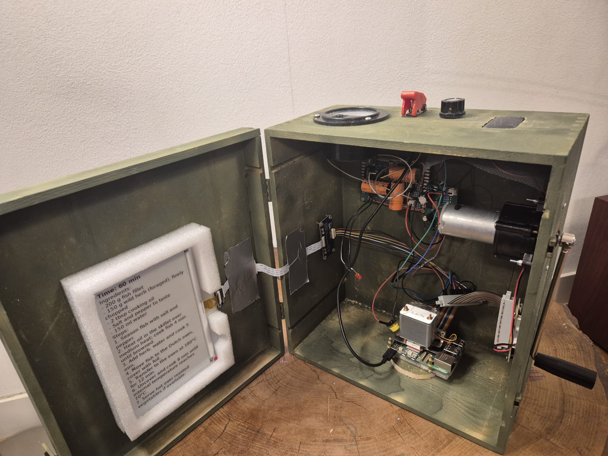 Inside the OutdoorGPT box: a Raspberry Pi, a hand-crank generator, an analog voltmeter, a speaker and hand-wired electronics in an olive-green wooden case.
